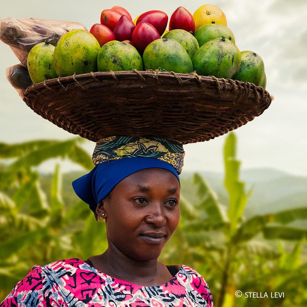 Photo of a woman in Rwanda carrying a basket of fruit on her head